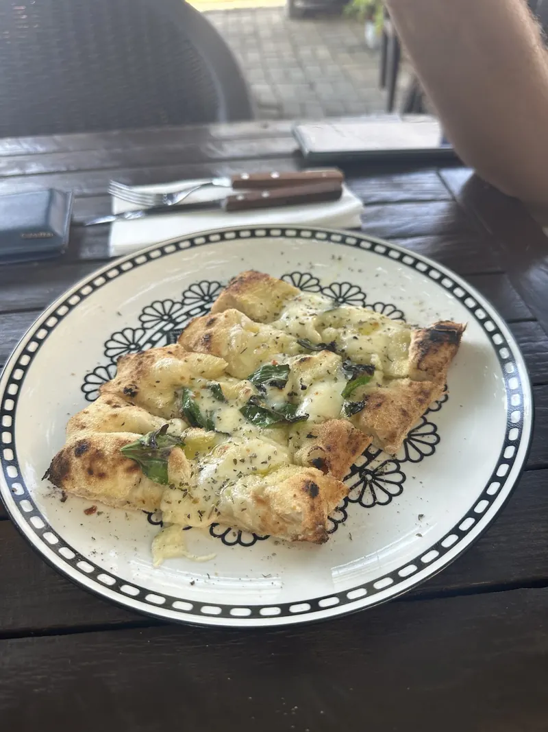 A white pizza with cheese and greens on a patterned plate