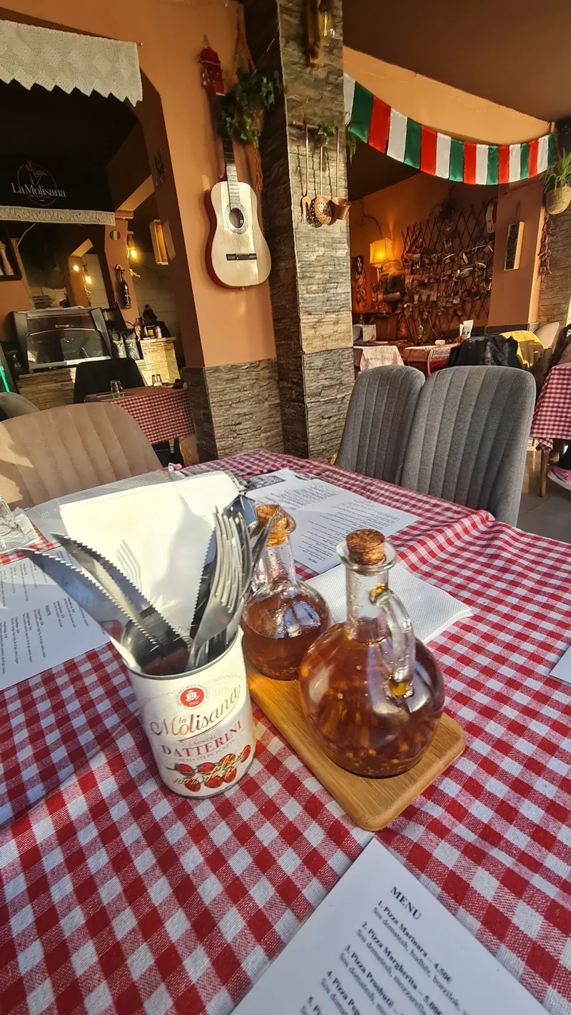 A red-checked table with olive oil, a tin of La Molisana tomatoes and the menu