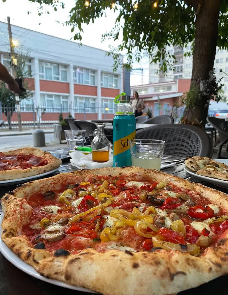 A Vegetariana pizza on the street-side terrace, with drinks and string lights